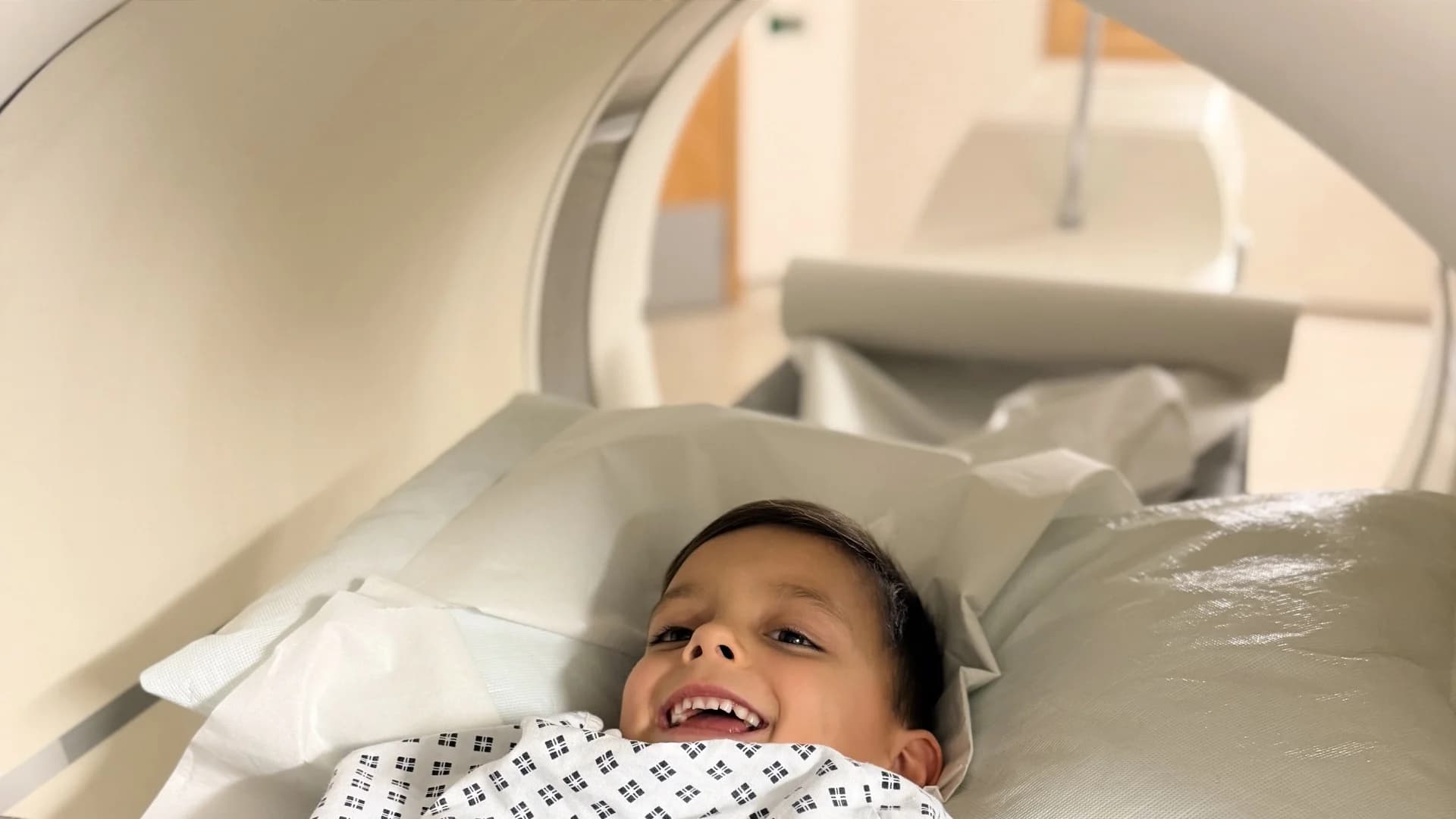 Aleks smiling brightly during his MRI scan, showing his incredible courage and positive spirit